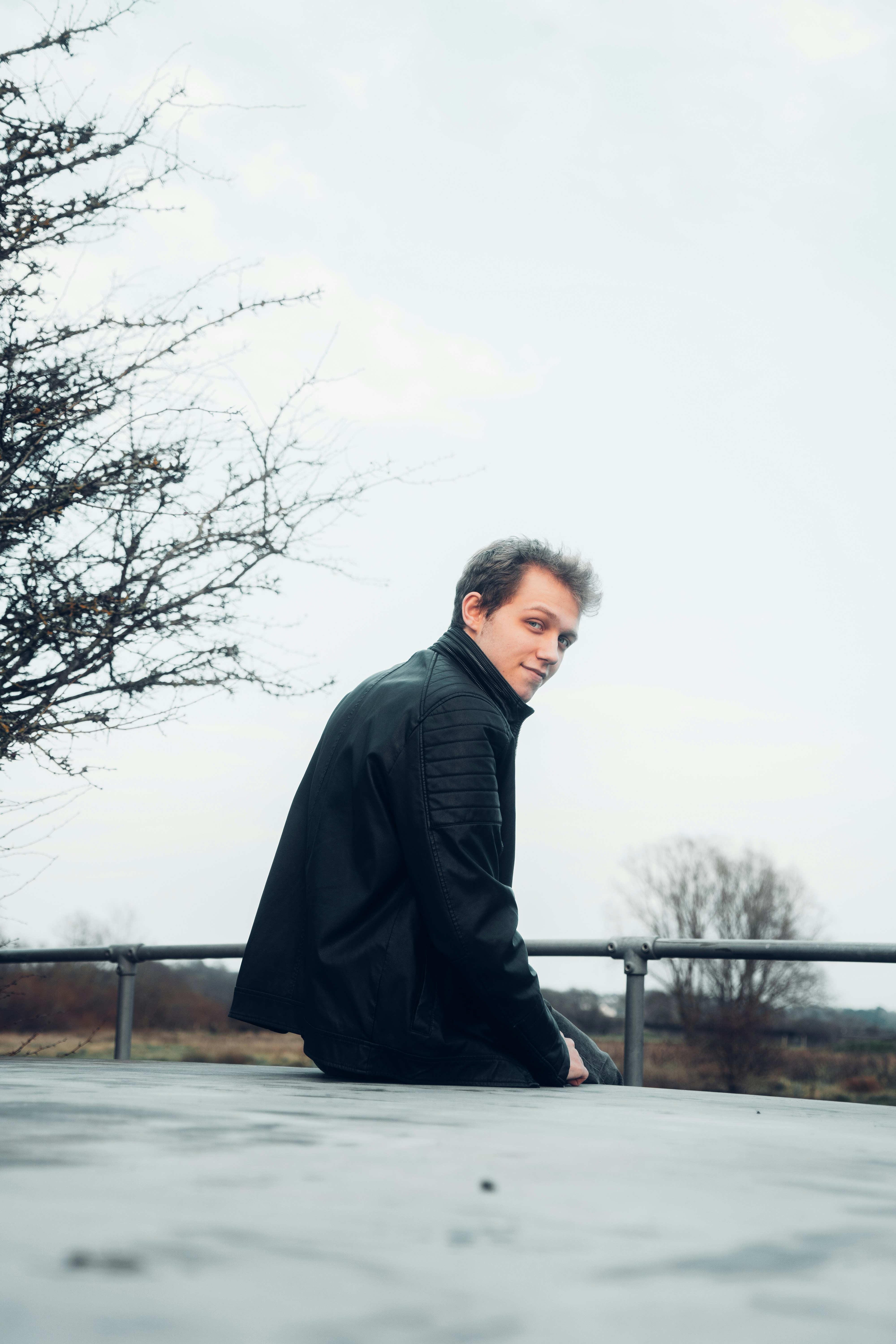 man in black coat standing near bare tree during daytime